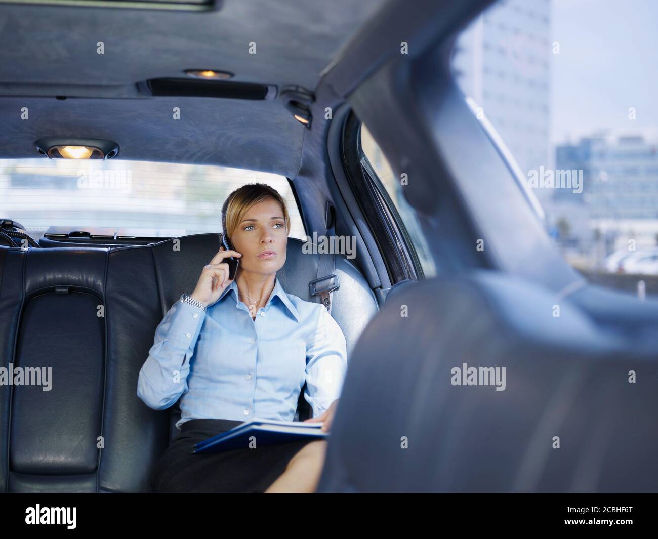 Mujer de negocios hablando por teléfono móvil viajando en limusina Foto de stock