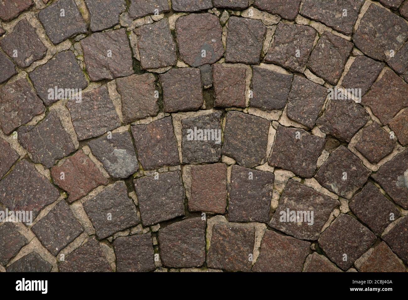 Cantería de pared o carretera. Las piedras de granito oscuro están dispuestas en forma de semicírculo y llenas de mortero de cemento. Primer plano. Textura abstracta o. Foto de stock