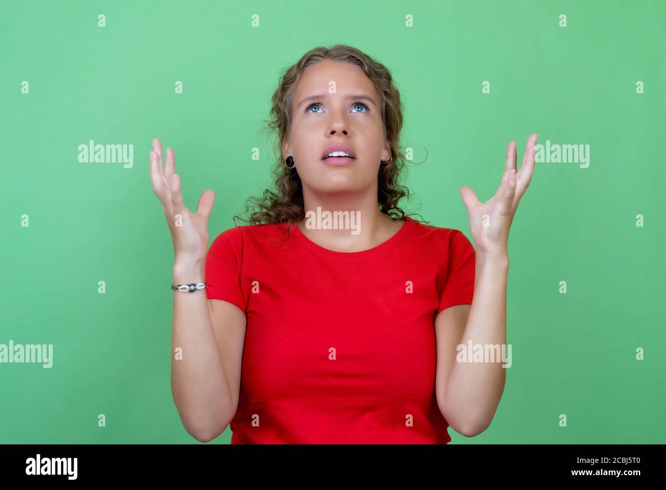 Mujer rubia enojada y estresada con camisa roja aislada fondo verde Foto de stock