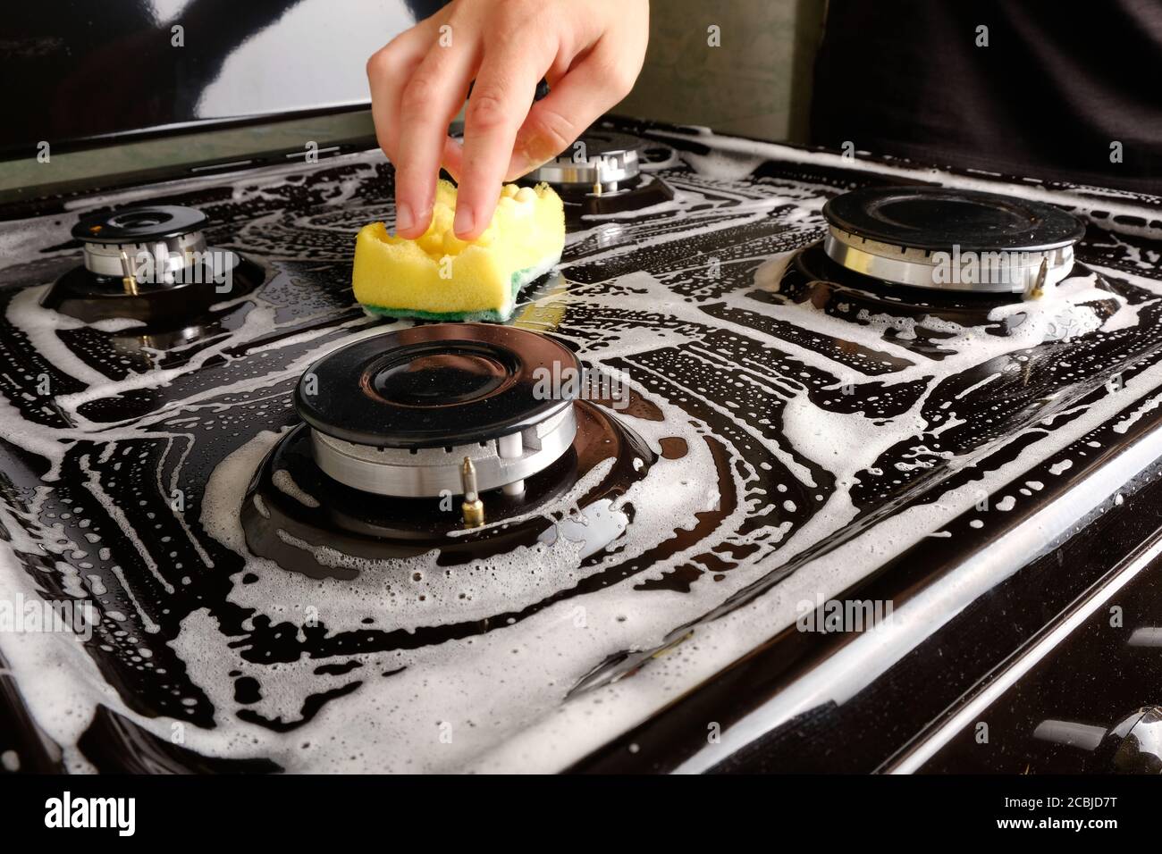 lavar la superficie en una estufa de gas, limpiar la superficie con un paño  amarillo, espuma blanca Fotografía de stock - Alamy