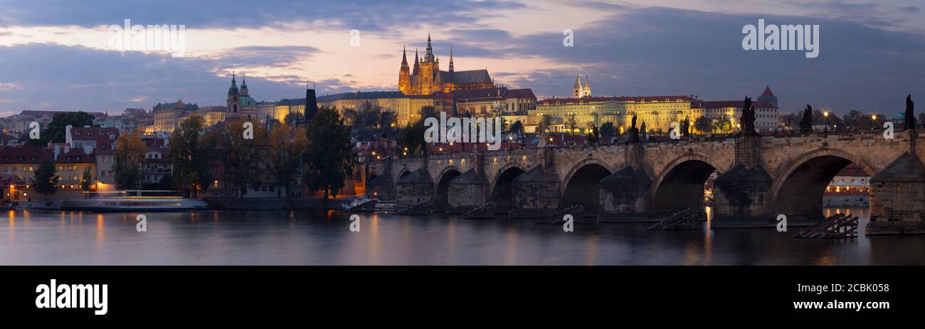 Praga - el panorama del Puente de Carlos, el Castillo y la Catedral desde el paseo marítimo sobre el río Vltava al atardecer. Foto de stock