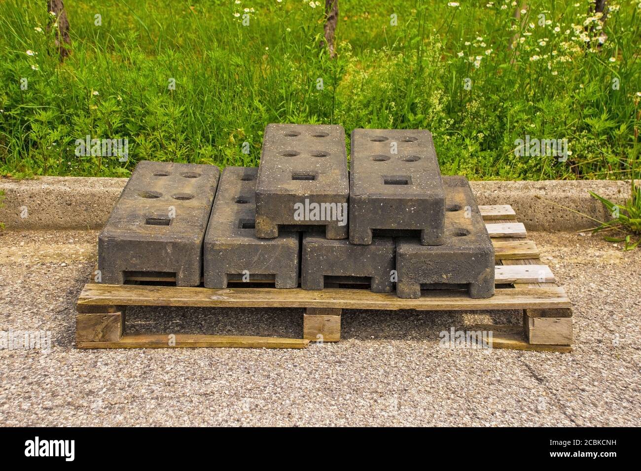 Bases de postes de cercado temporales de concreto ponderado para paneles de cercado de bloqueo en palets de madera en el sitio de obras de sustitución de alcantarillas En el NE de Italia Foto de stock