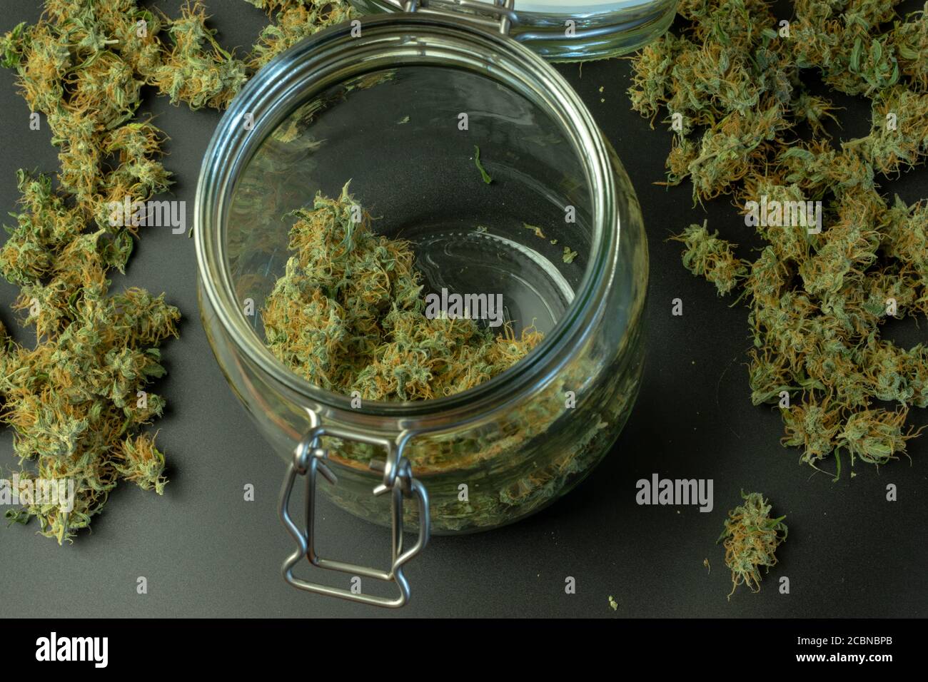 Vista superior de brotes de cannabis en tarro de vidrio con marihuana en el fondo Foto de stock