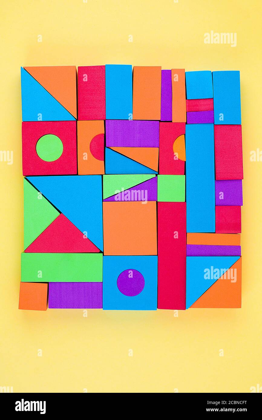 Niños diseñador de multicolores volumétricos 3d formas geométricas sobre un fondo amarillo. Juego educativo lógico. Foto de stock