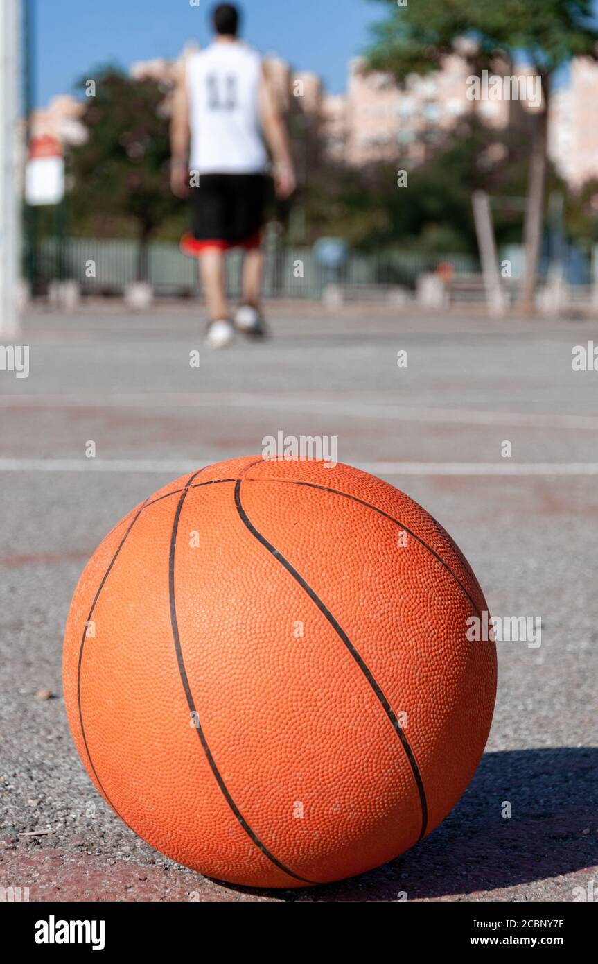 Disparo de enfoque selectivo vertical de una pelota de baloncesto en un  tribunal y una persona en el fondo Fotografía de stock - Alamy