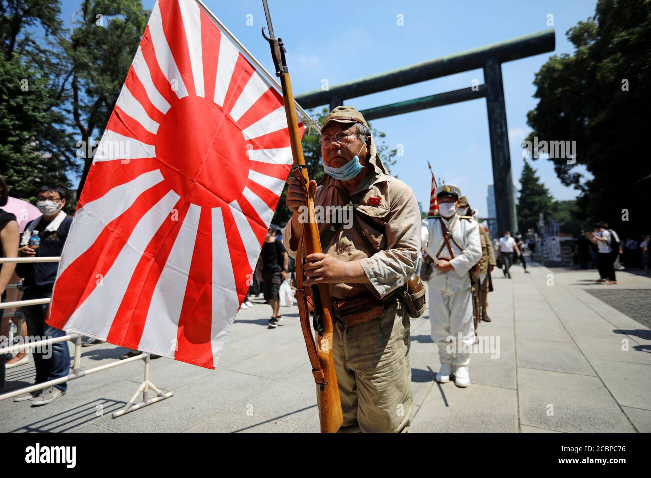 Un hombre vestido con uniforme militar imperial japonés y llevando la  bandera del sol naciente de Japón visita Yasukuni Shrine en el 75º  aniversario de la rendición de Japón en la Segunda