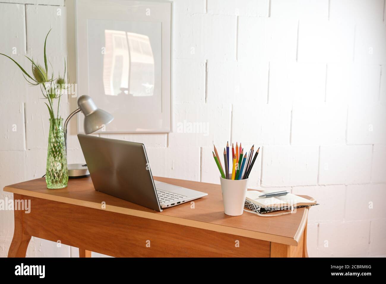 Pequeño escritorio de oficina de madera desde atrás con portátil y  herramientas contra una pared blanca rugosa, espacio de copia, enfoque  seleccionado, profundidad de campo estrecha Fotografía de stock - Alamy