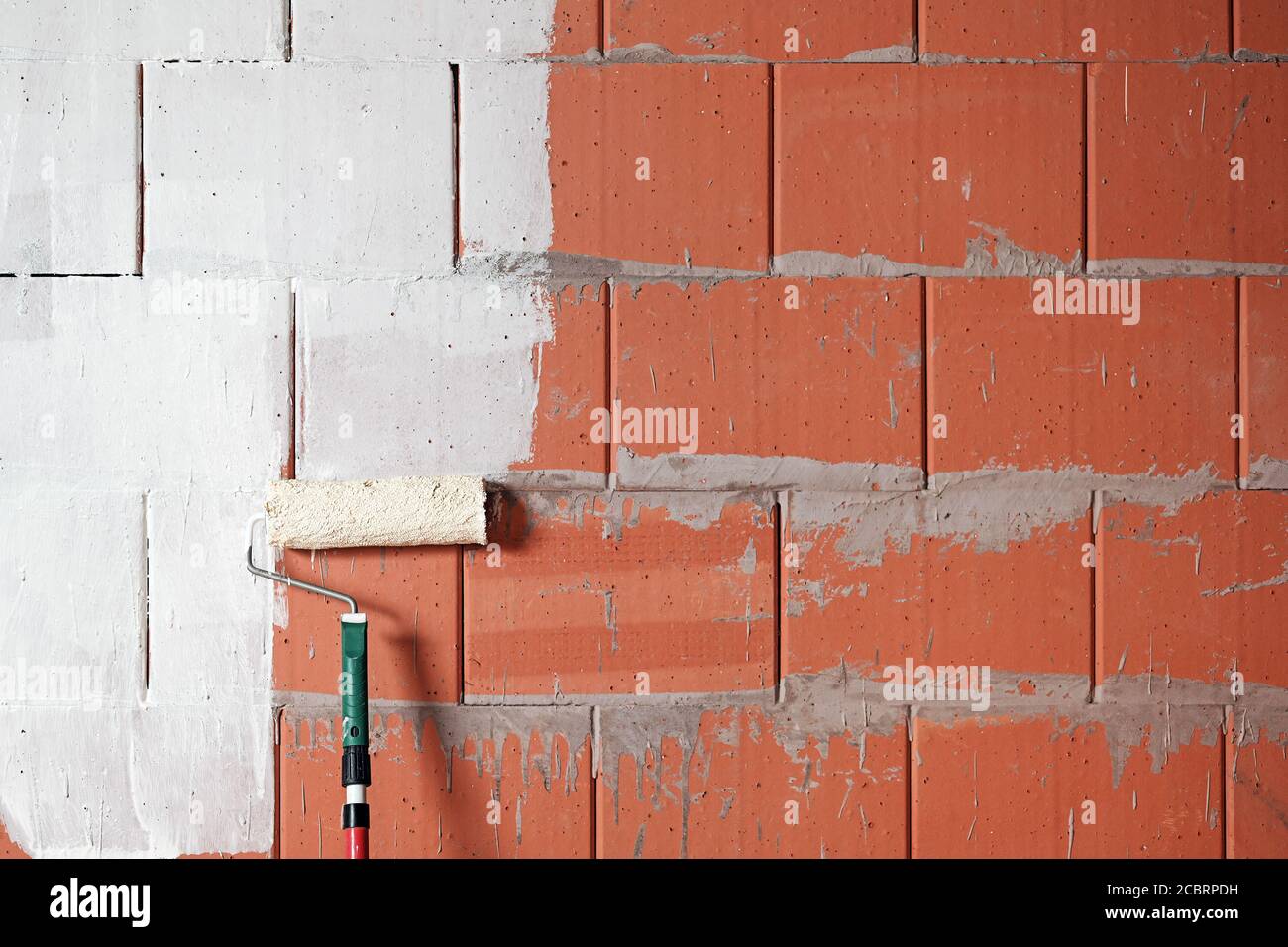 Pintura de una pared de ladrillo blanco con un rodillo de pintura en un  sitio de construcción, concepto de fondo para la renovación, el edificio y  el hogar, espacio de copia Fotografía