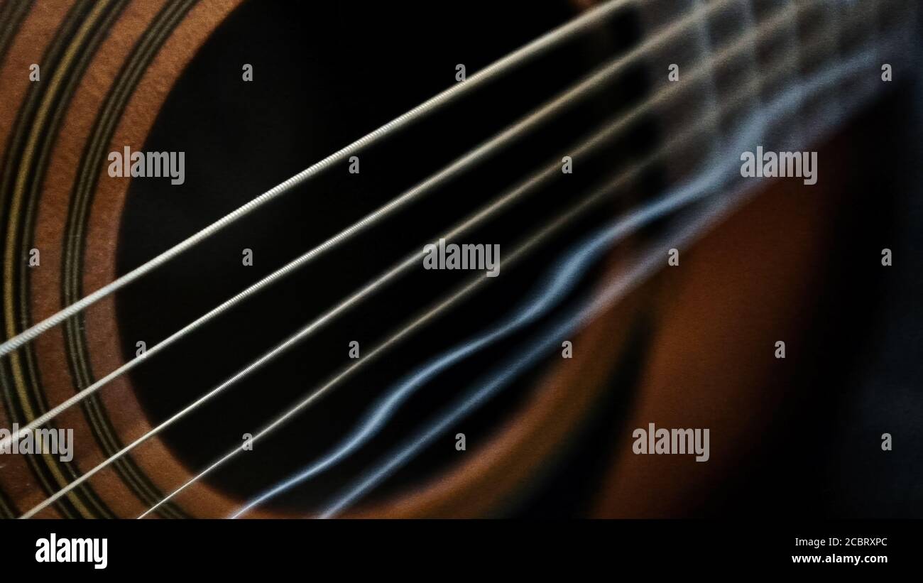 Primer plano de cuerdas de guitarra onduladas que se ven en el sonido  agujero de guitarra acústica Fotografía de stock - Alamy