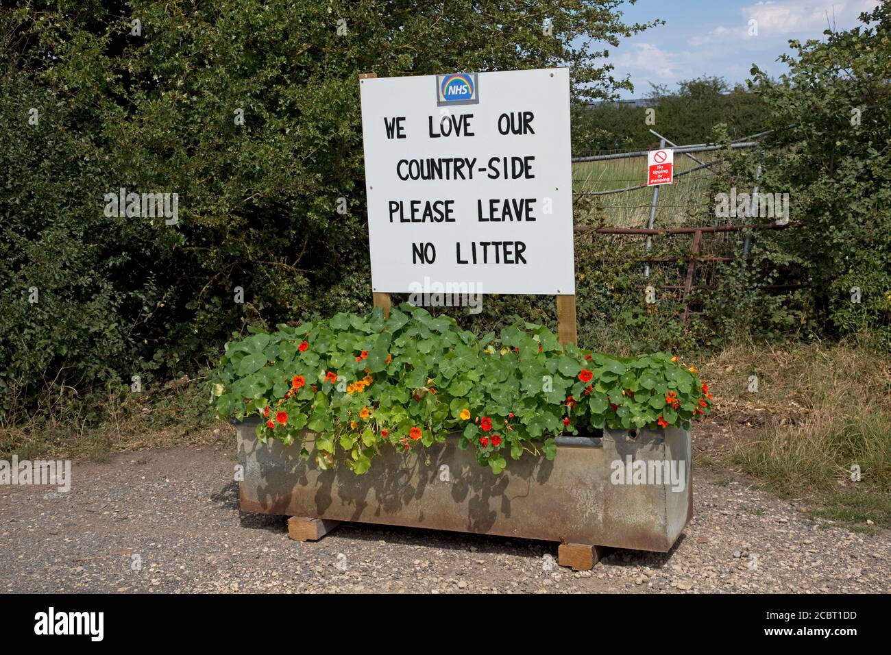 Por favor, no deje basura - nos encanta nuestro aviso de campo Con el logo NHS montado en layby en la vieja canaleta de beber Lleno de flores cerca de Stratford Upon Avo Foto de stock