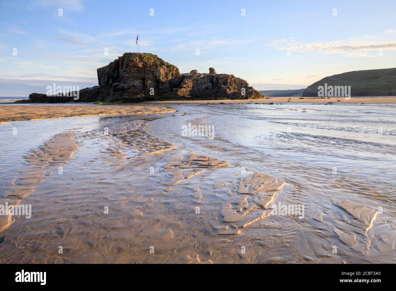 Chapel Rock en la playa de Perranporth en Cornwall capturado en una mañana a mediados de julio con los patrones de arena como interés de primer plano. Foto de stock