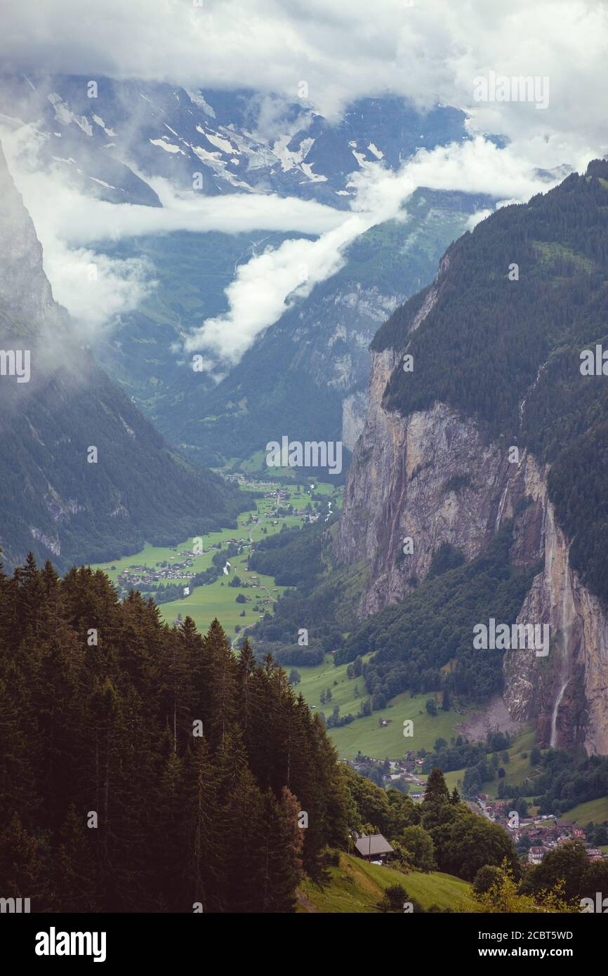 Vista en ángulo alto sobre el valle Lauterbrunnen en las tierras altas de Bernese con nubes bajas colgantes y niebla en verano. Visto desde el lado este mientras se hace senderismo Foto de stock