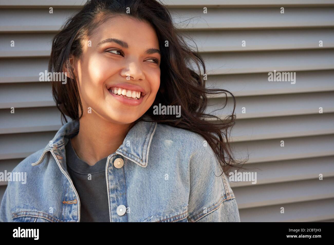 Sonriendo joven afroamericana adolescente mirando fuera riendo, con la cabeza. Foto de stock