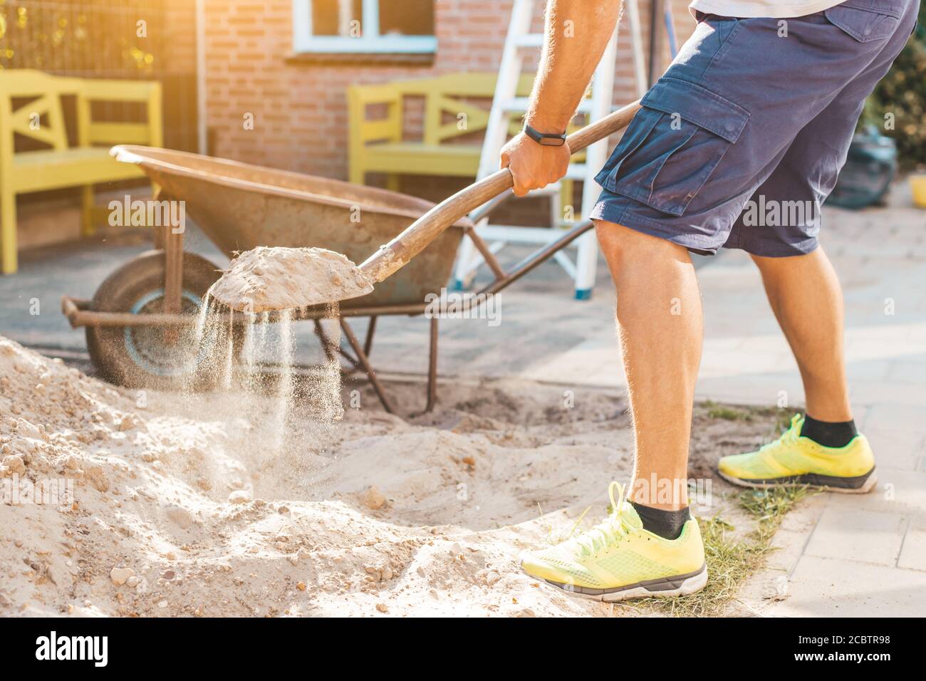 Imagen recortada del hombre cavando arena con una pala - DIY hágalo usted mismo y el concepto de las obras caseras Foto de stock