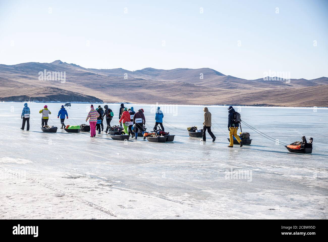 Un grupo de turistas con trineos de hielo caminando sobre la superficie congelada del lago Baikal, Rusia Foto de stock