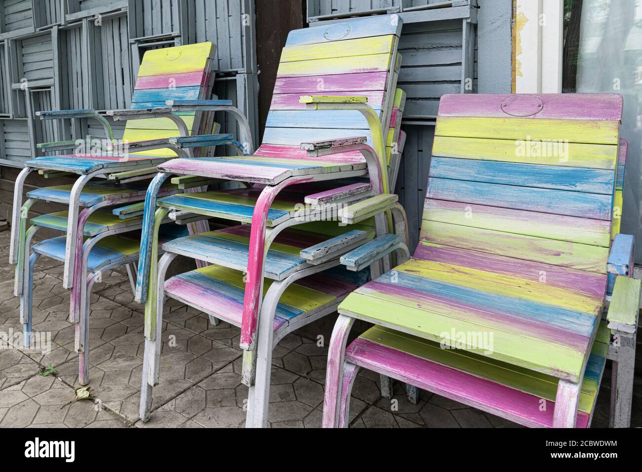 Las sillas de madera, pintadas a mano en diferentes colores, están apiladas  en la terraza Fotografía de stock - Alamy