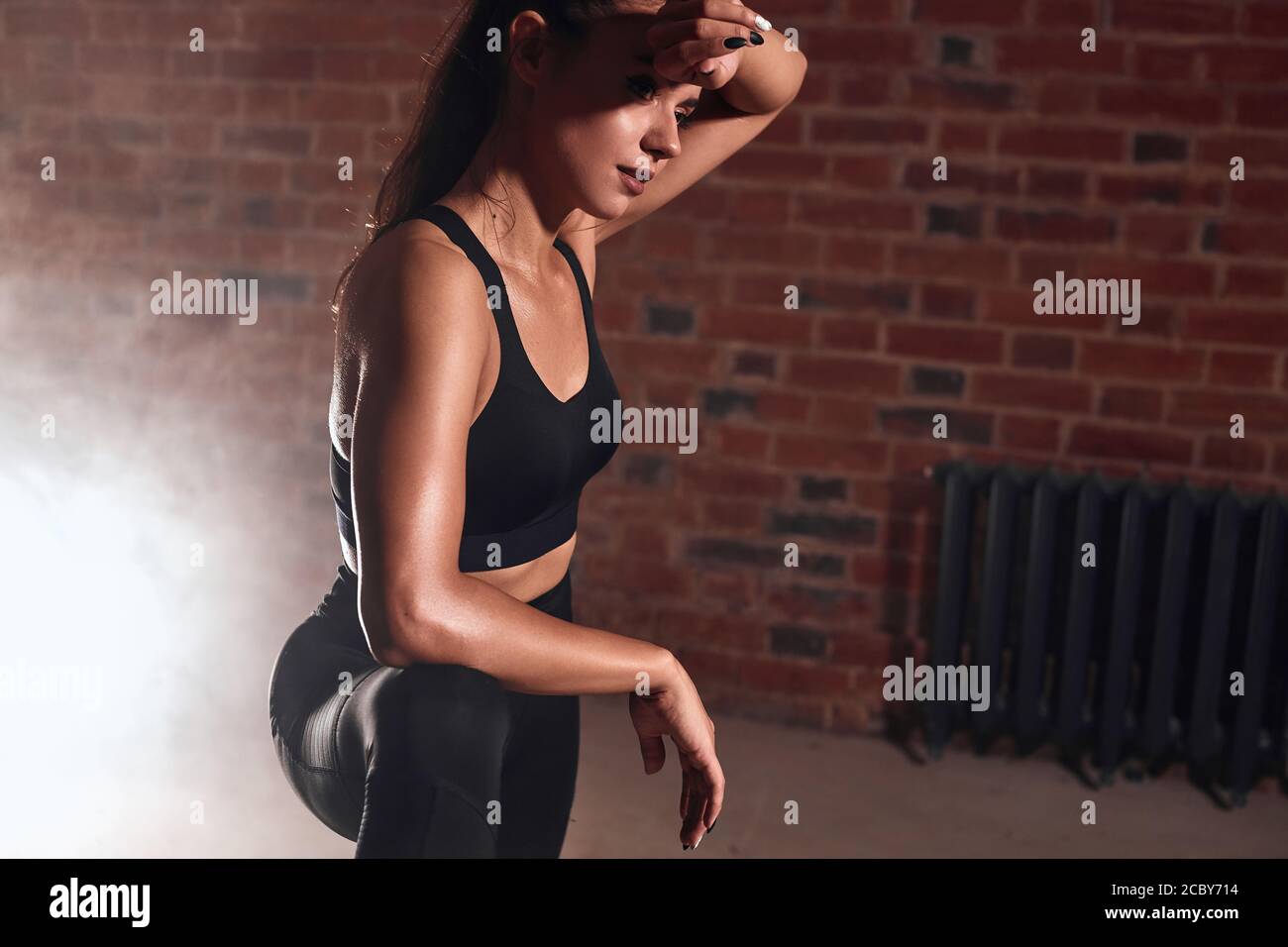 Mujer agotada en ropa deportiva tomar descanso después de hacer ejercicio  en el gimnasio. Mujer deportiva sosteniendo la mano en la cabeza, limpia el  sudor de la frente. Concepto Crossfit. BRIC Fotografía
