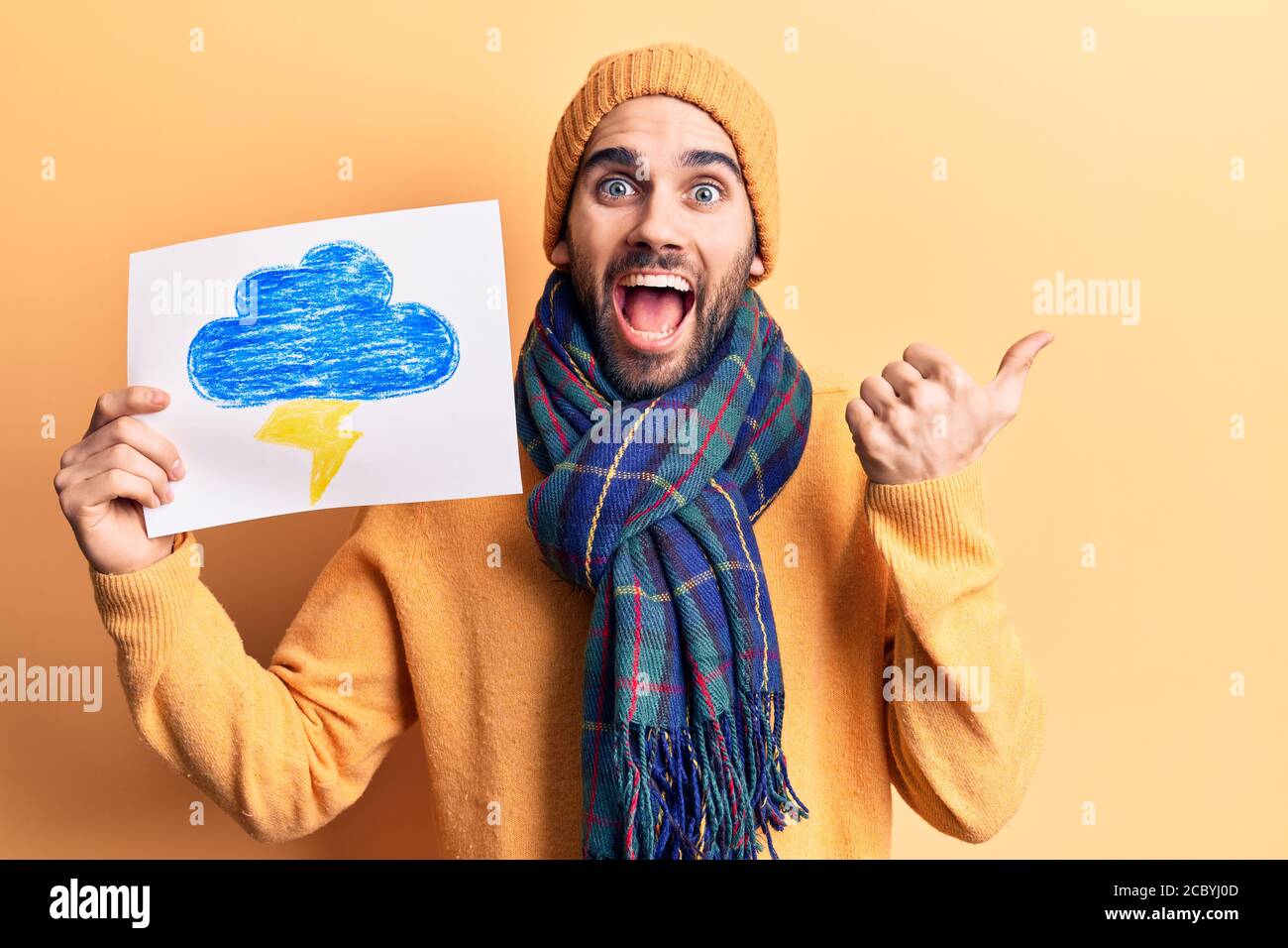 Joven hombre guapo con barba con ropa de invierno que sostiene trueno  dibuja el pulgar apuntando hacia el lado sonriendo feliz con boca abierta  Fotografía de stock - Alamy