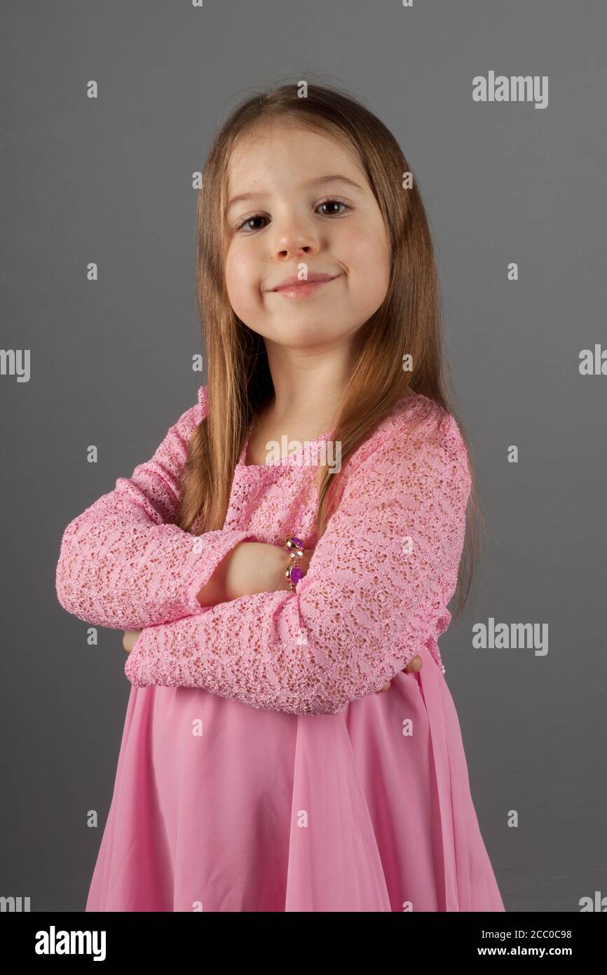 Encantadora niña en un vestido rosa sobre gris natural antecedentes Foto de stock