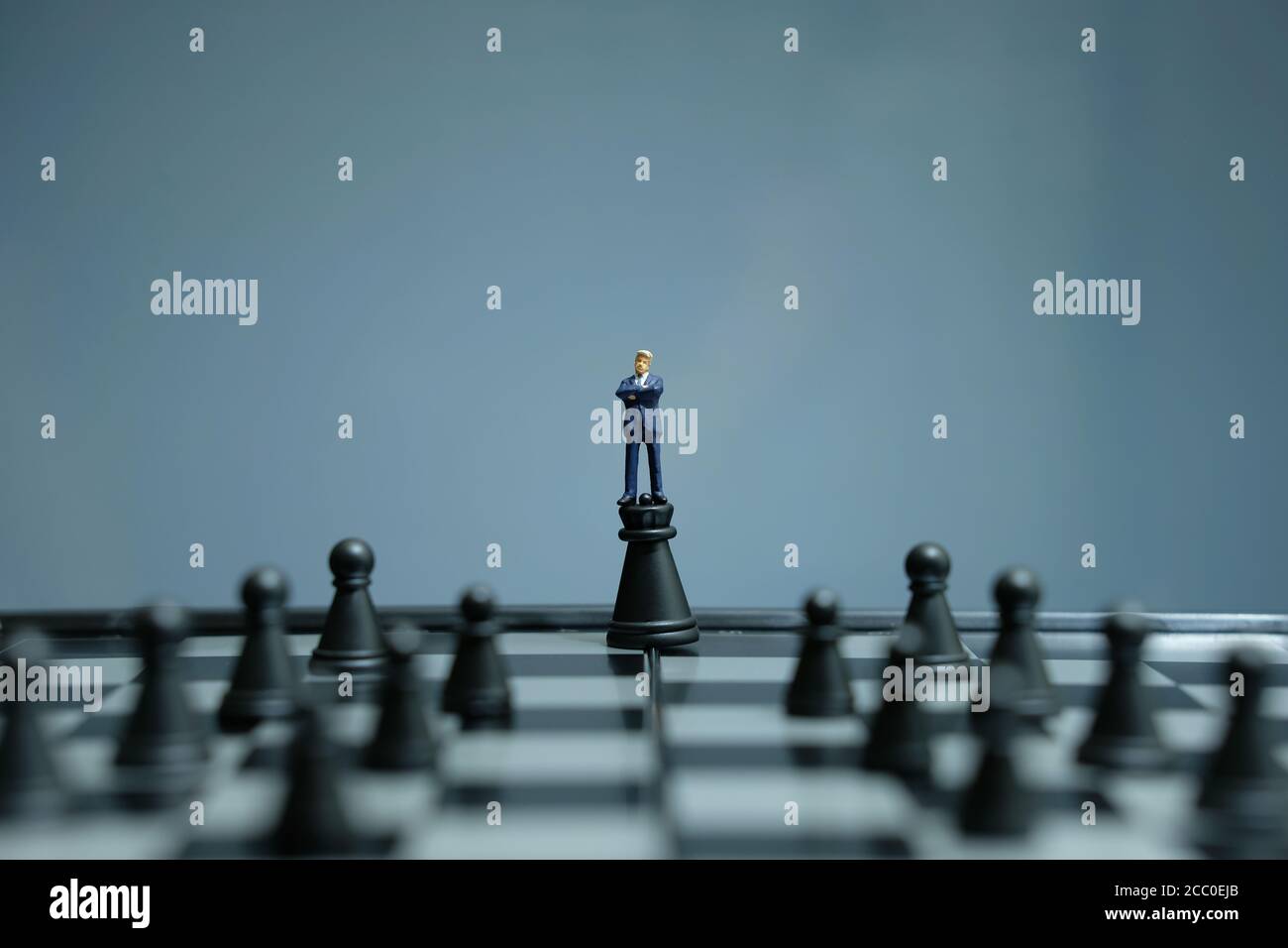 Estrategia de negocios foto conceptual - hombre de negocios en miniatura de pie sobre el castillo peón en medio del tablero de ajedrez Foto de stock