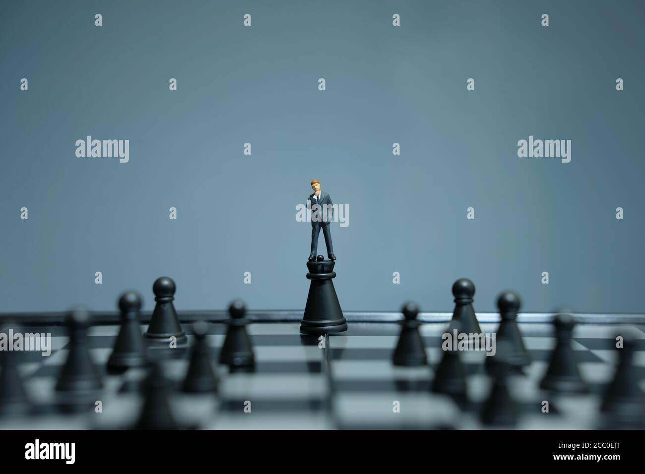 Estrategia de negocios foto conceptual - hombre de negocios en miniatura de pie sobre el castillo peón en medio del tablero de ajedrez Foto de stock