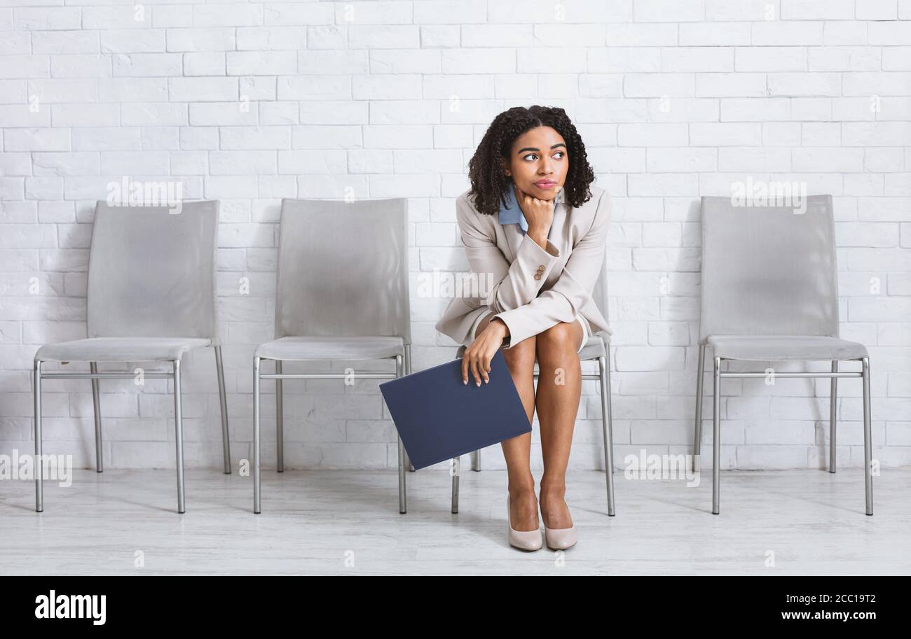 Una mujer afroamericana aburrida con ropa formal esperando su entrevista de  trabajo para empezar en la oficina corporativa, espacio de copia Fotografía  de stock - Alamy