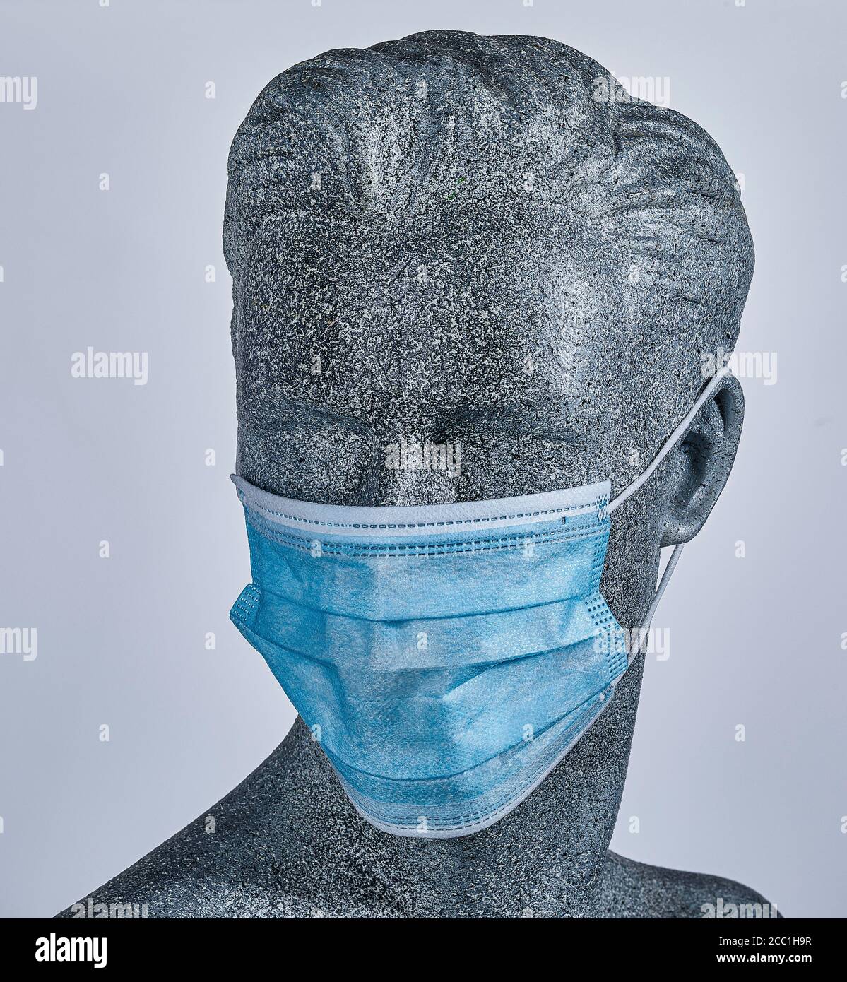 Pantalla masculina ficticia, con una máscara médica protectora, sobre fondo gris Foto de stock
