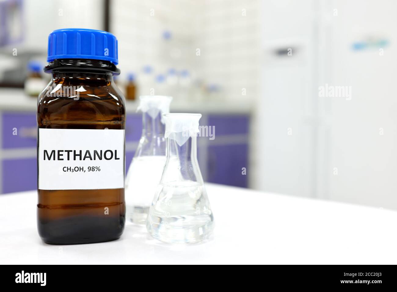 Foco selectivo de metanol en botella de vidrio ámbar marrón dentro de un laboratorio. Fondo borroso con espacio de copia. Foto de stock