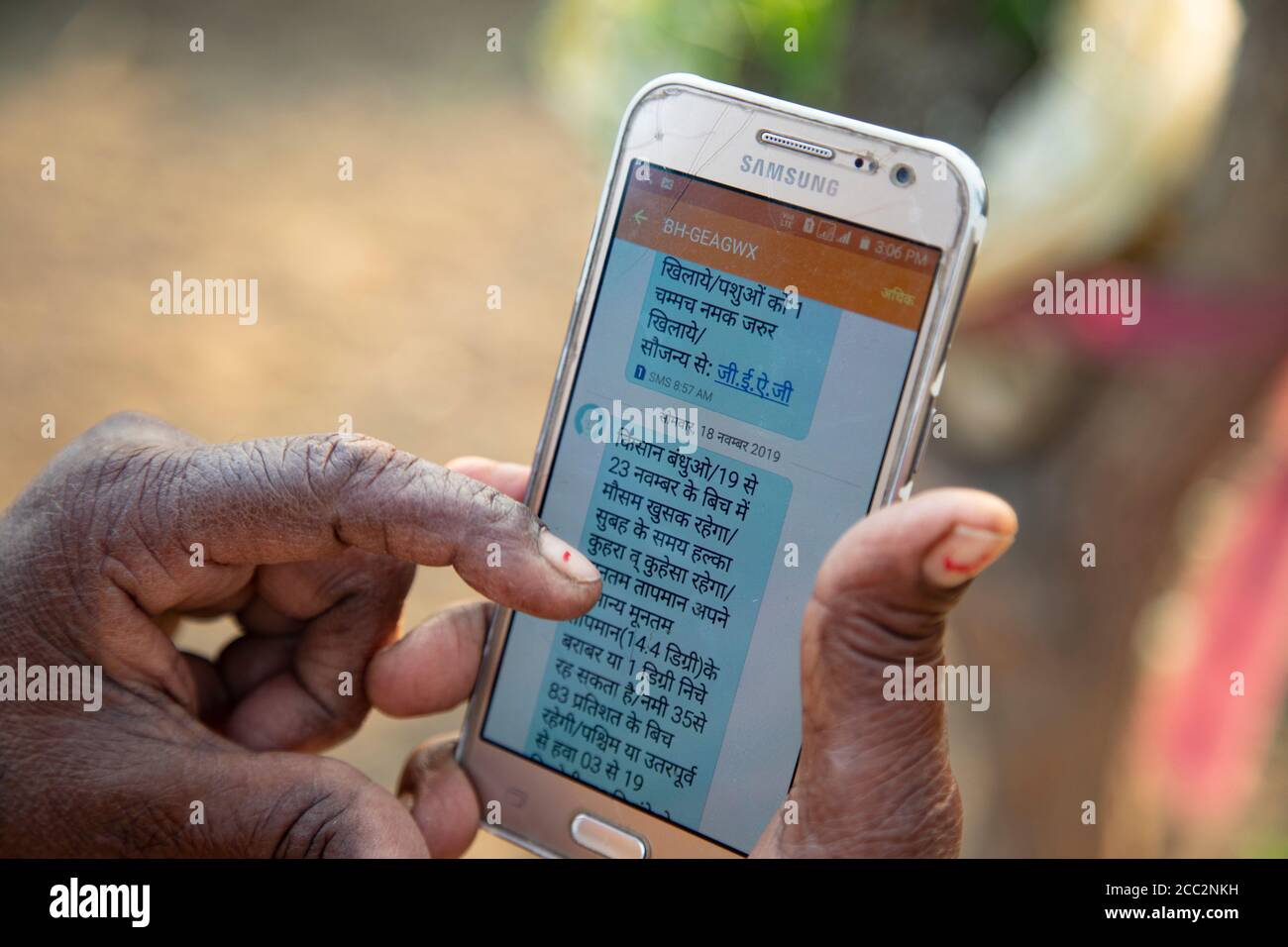 Una anciana lee un mensaje de texto enviado a ella en su teléfono móvil como parte del sistema de alerta temprana establecido por el proyecto de resistencia a las inundaciones transfronterizas de la LWR. Estos mensajes de texto se envían a los residentes de las comunidades que viven en las cuencas de los ríos Gandak y Koshi para que reciban información precisa sobre los pronósticos meteorológicos de la zona y los niveles de inundación río arriba. Foto de stock