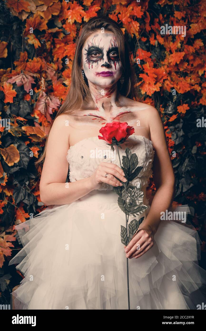 vértice garrapata Maldito Horrible maquillaje en una chica con rosa en un vestido de novia para  Halloween Fotografía de stock - Alamy