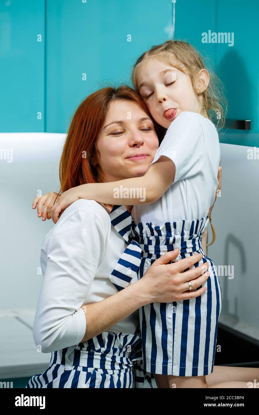 Hermosa madre e hija están abrazando y sonriendo con alegría, sentados