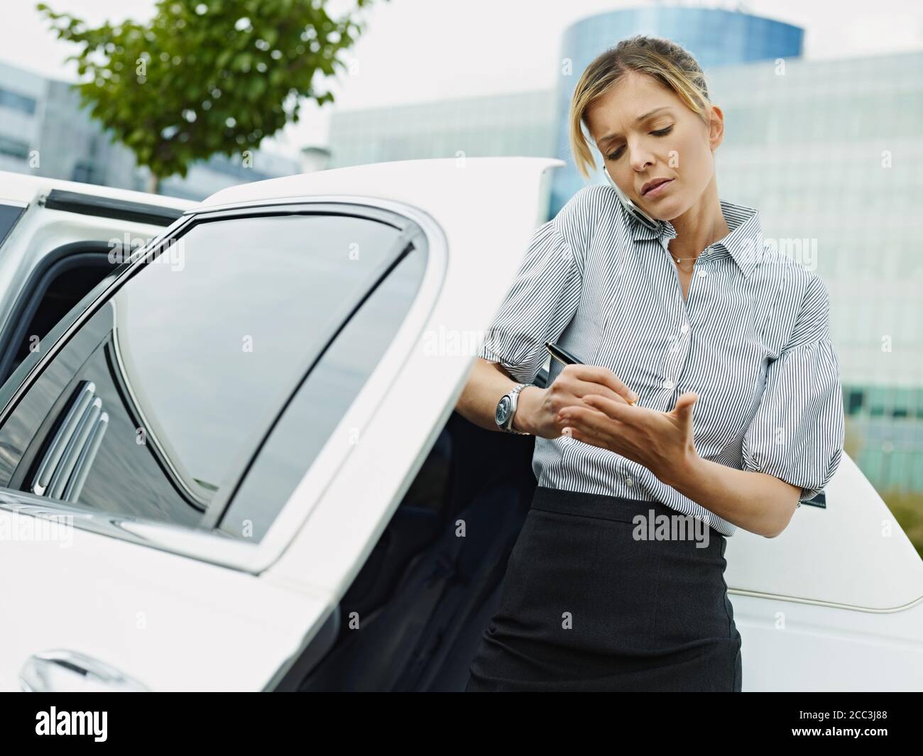 La mujer de negocios toma notas en la palma de la mano durante la llamada telefónica Foto de stock