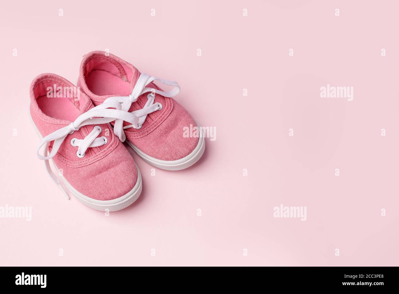 Zapatos rosas para bebés sobre fondo rosa, concepto de primeros pasos, cumpleaños, expectativa, embarazo, maternidad, maternidad, paternidad. Tarjeta monocroma para b Foto de stock