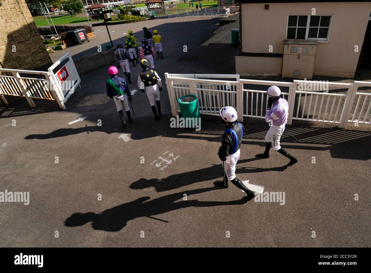 Los jinetes salen del vestuarios y hacen el paseo hasta el anillo del desfile en el hipódromo de Fontwell Park. Foto de stock