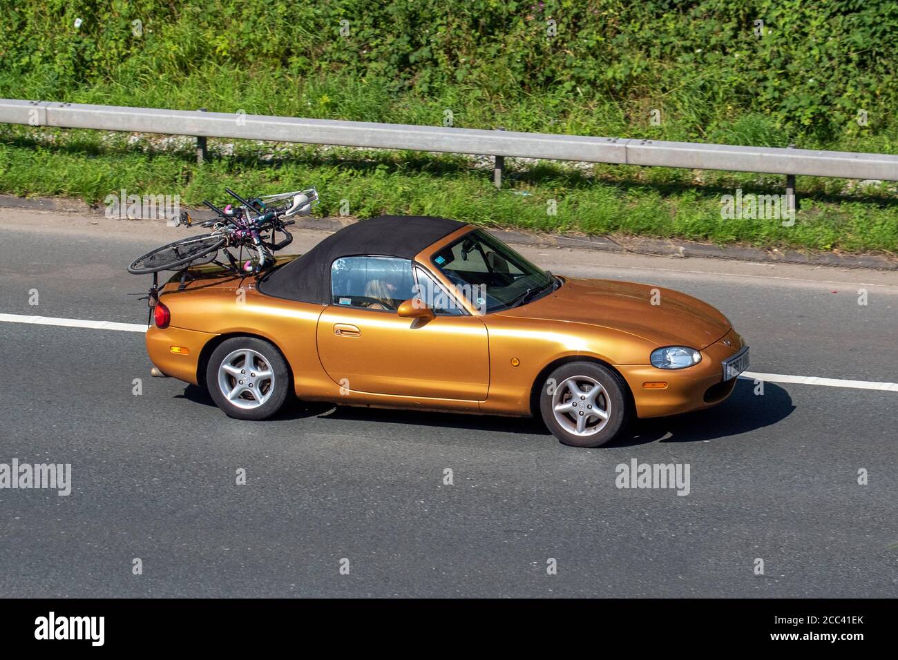 1999 oro Mazda MX-5 con portabicicletas; vehículos de circulación,  vehículos de conducción en carreteras del Reino Unido, motores,  motorización en la red de autopistas M6 Fotografía de stock - Alamy