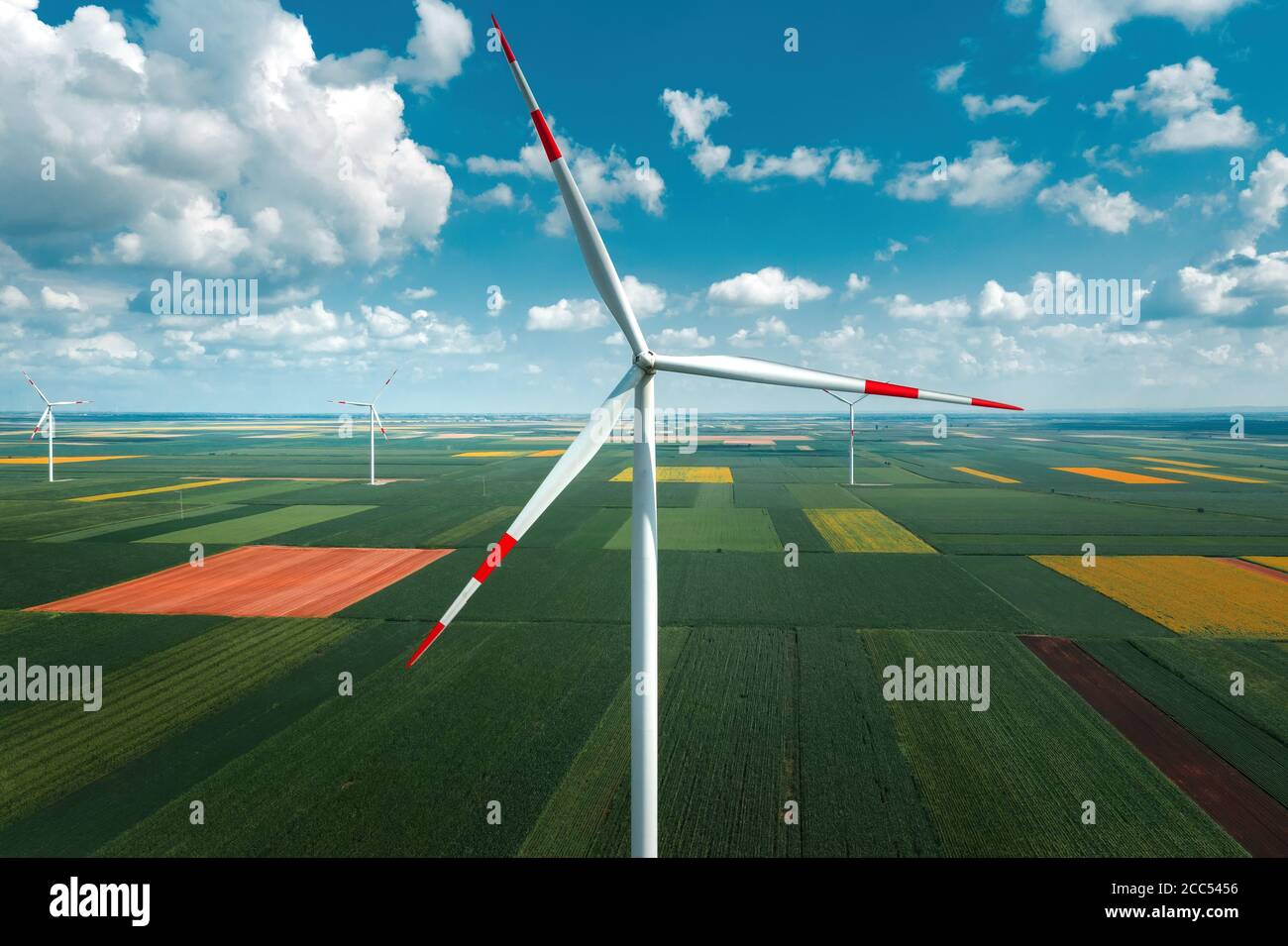 Vista aérea de los aerogeneradores en el parque eólico moderno desde la pov de los aviones, visión de gran angular de la innovadora tecnología de recursos sostenibles Foto de stock