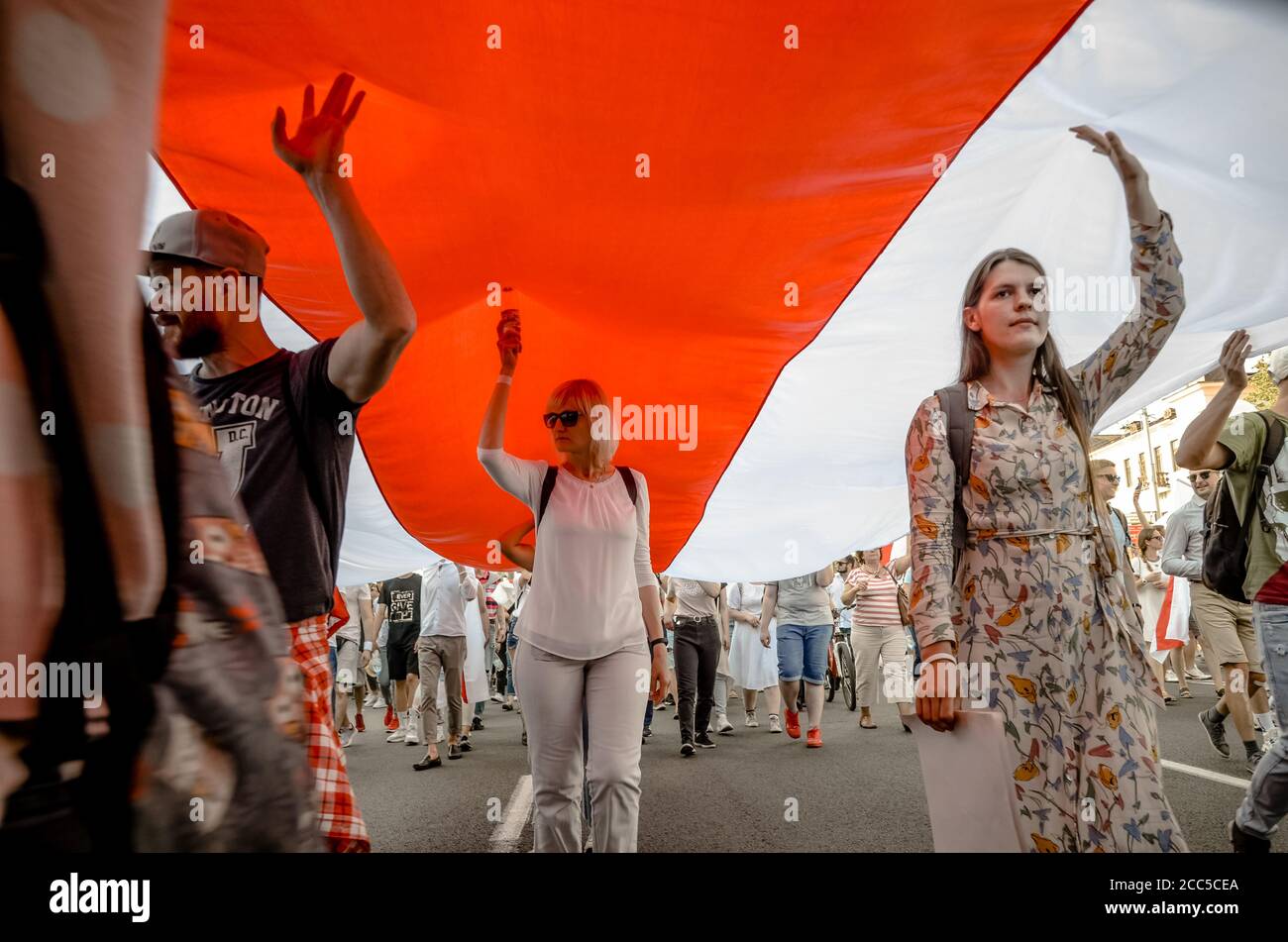 Minsk, Bielorrusia - 16 de agosto de 2020: El pueblo bielorruso lleva bandera histórica gigante de Bielorrusia. Participan en protestas pacíficas después de la presidencia de el Foto de stock