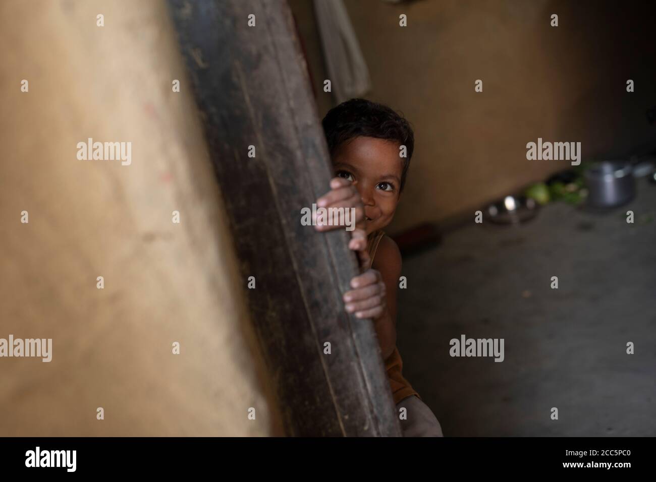 Un niño de cuatro años de edad se apareaba de la puerta de su casa en Bihar, India, Asia del Sur. Foto de stock