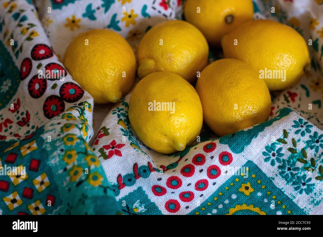 Manojo de limones en el colorido mantel sentado en la mesa con fondo marrón borroso Foto de stock