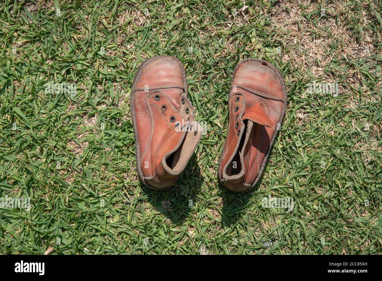 Vista superior de un par de botas marrones sin cordones. Botas de cuero de  niño viejo en la hierba Fotografía de stock - Alamy