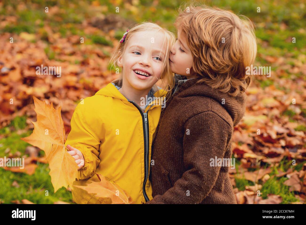 Un niño besando a una chica en el parque de otoño. A los niños les encanta el concepto. Foto de stock