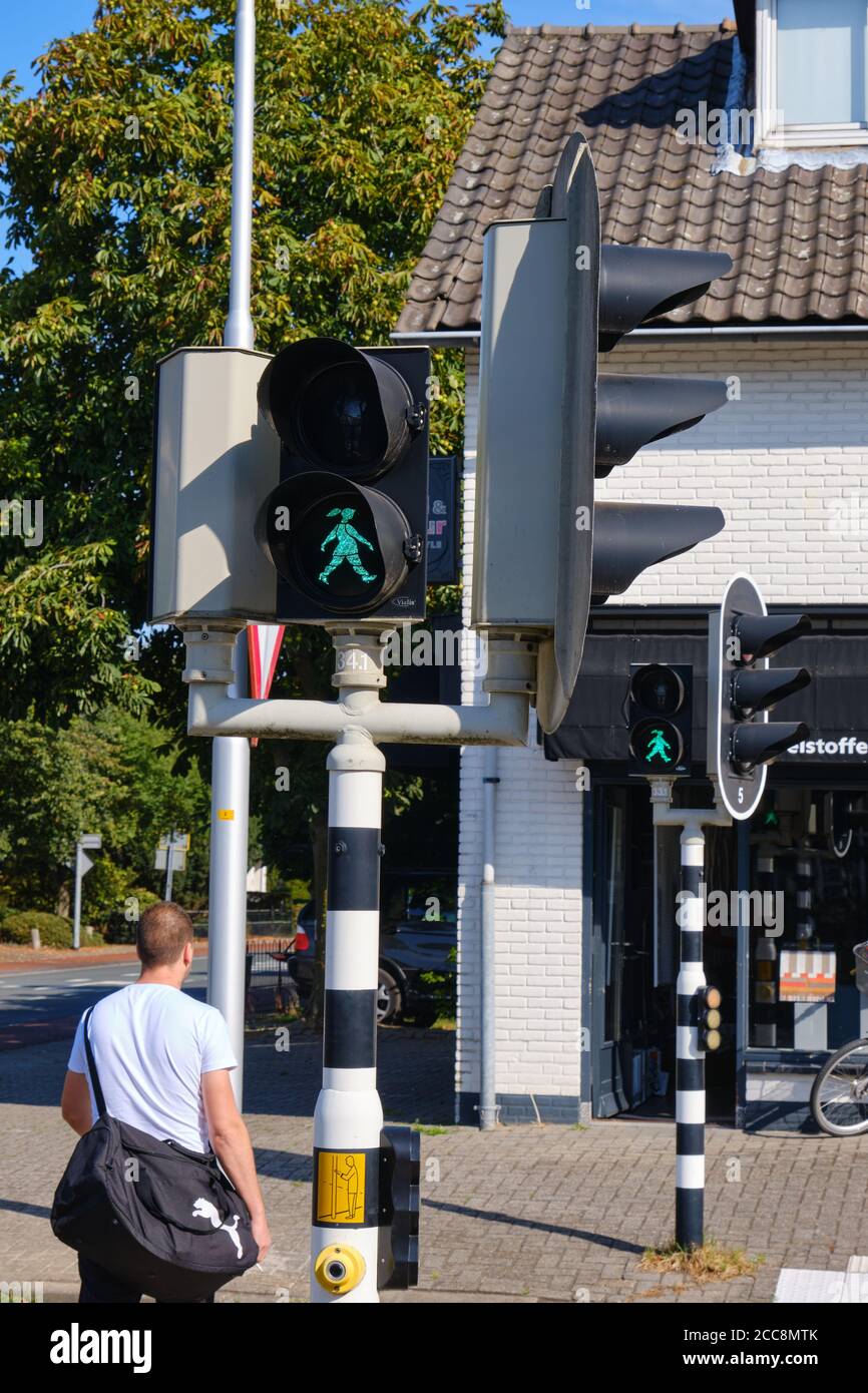 Bennekom,países Bajos,Ago,19,2020:Luz peatonal verde con una chica feliz caminando con cola de caballo en el cruce de los países Bajos. El nombre de la chica es Foto de stock