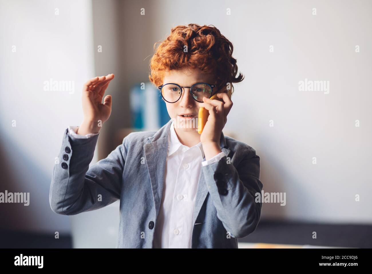Niño de pelo rojo en un traje que tiene una llamada telefónica Foto de stock