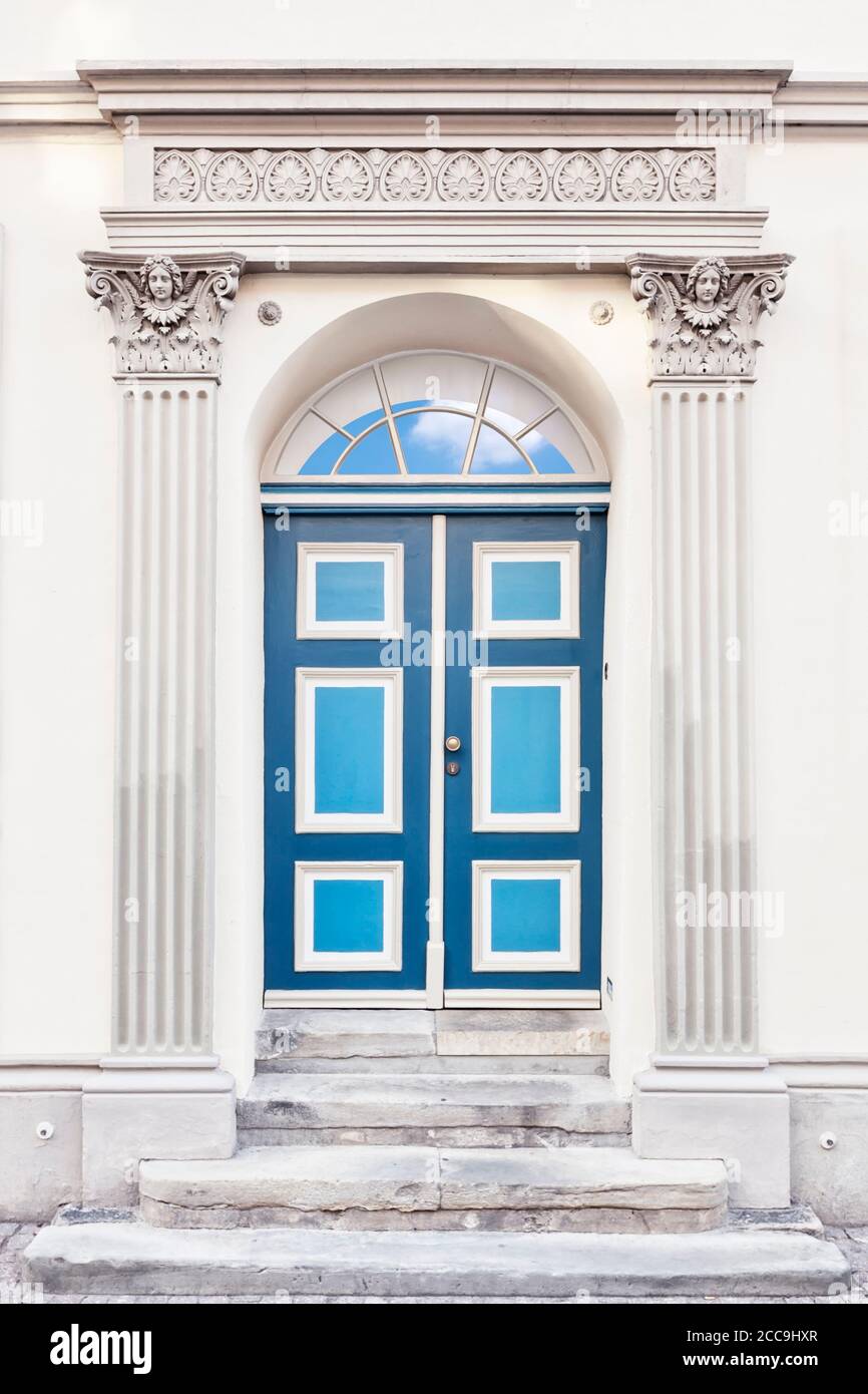 Portal neoclasicista con columnas griegas, que se compone con el cielo visible a través de la ventana por encima de la puerta Foto de stock