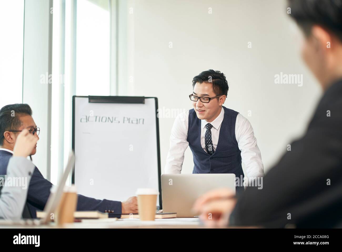 joven hombre de negocios asiático que facilita una discusión durante una reunión de equipo en la oficina Foto de stock