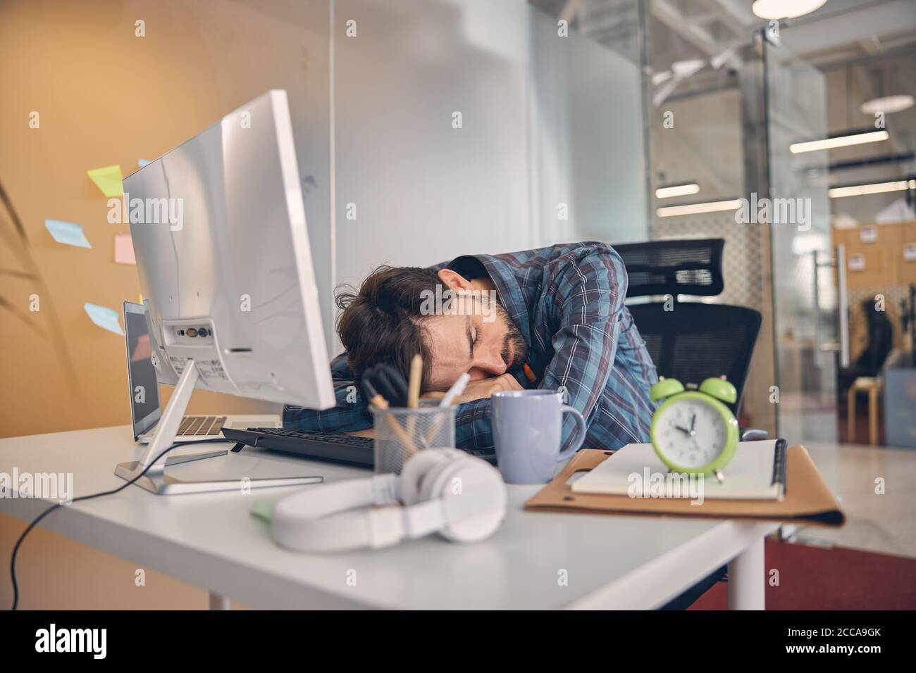 Exhausta, hombre joven con exceso de trabajo tomando una siesta en el cargo Foto de stock