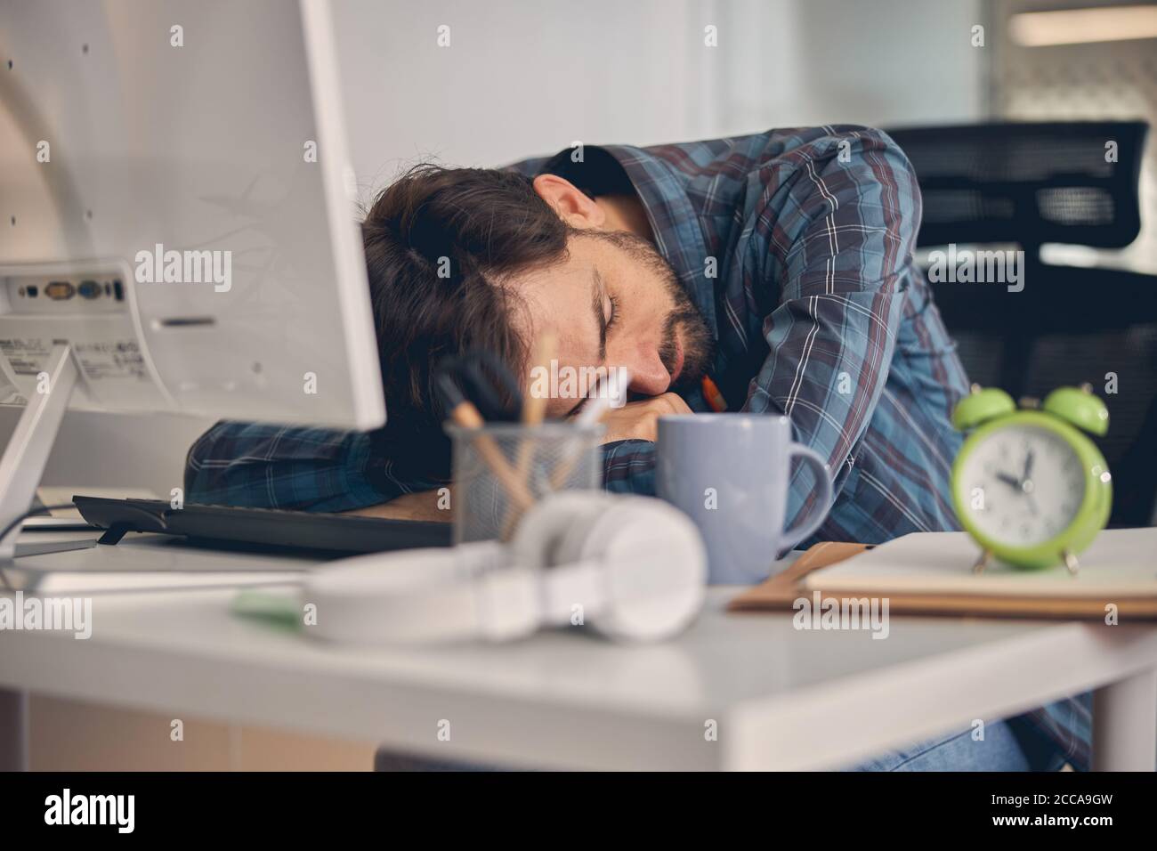 Un joven cansado tomando una siesta en el trabajo Foto de stock