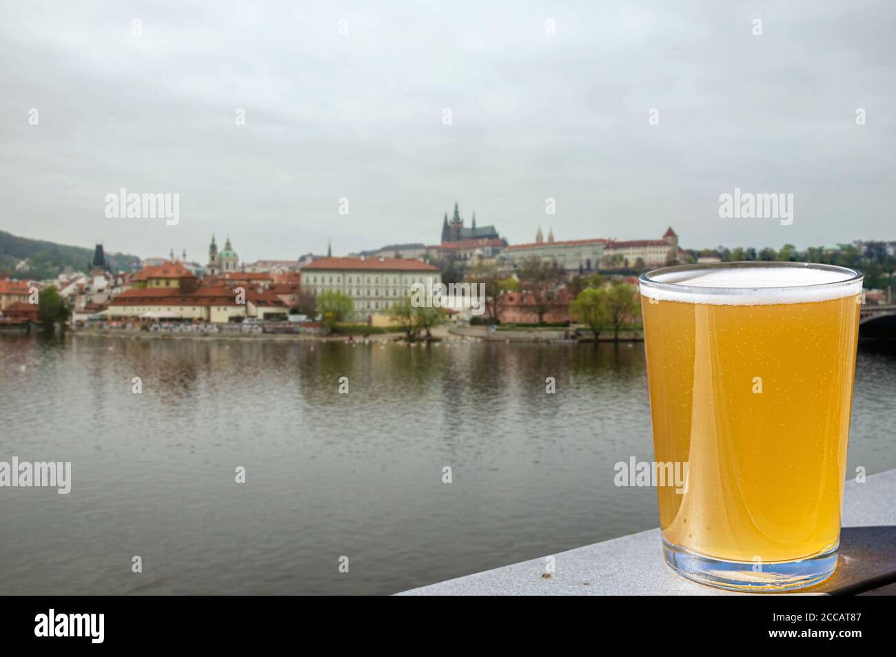 Copa de cerveza ligera con vistas al río y al centro de la ciudad de Praga, república Checa Foto de stock