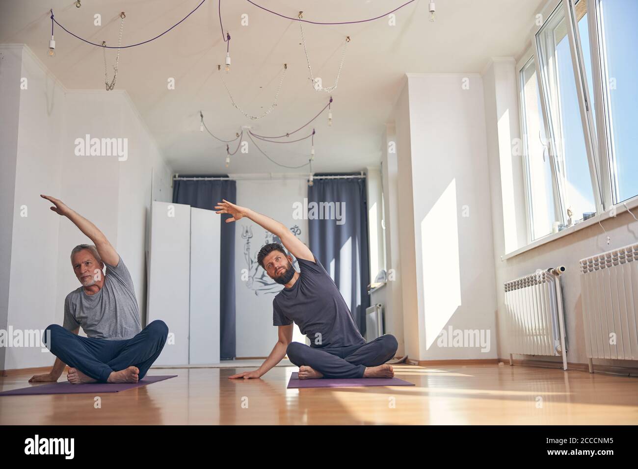 Dos hombres caucásicos flexibles practicando yoga juntos Foto de stock