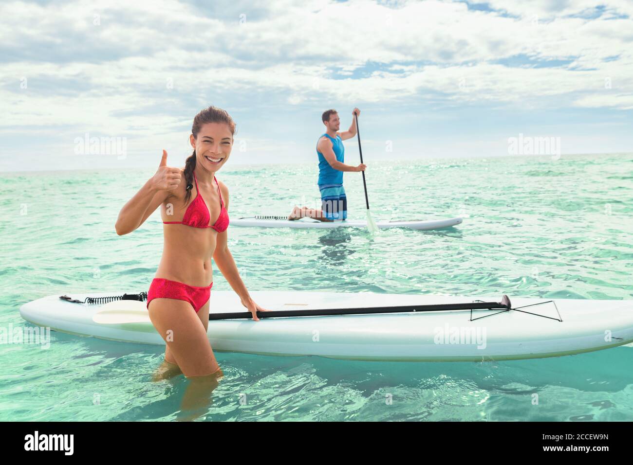 Playa de paddleboard gente en tablas de paddle surf en el océano en la playa de Hawaii. Raza mixta pareja mujer y el hombre caucásico disfrutando de deportes acuáticos Foto de stock
